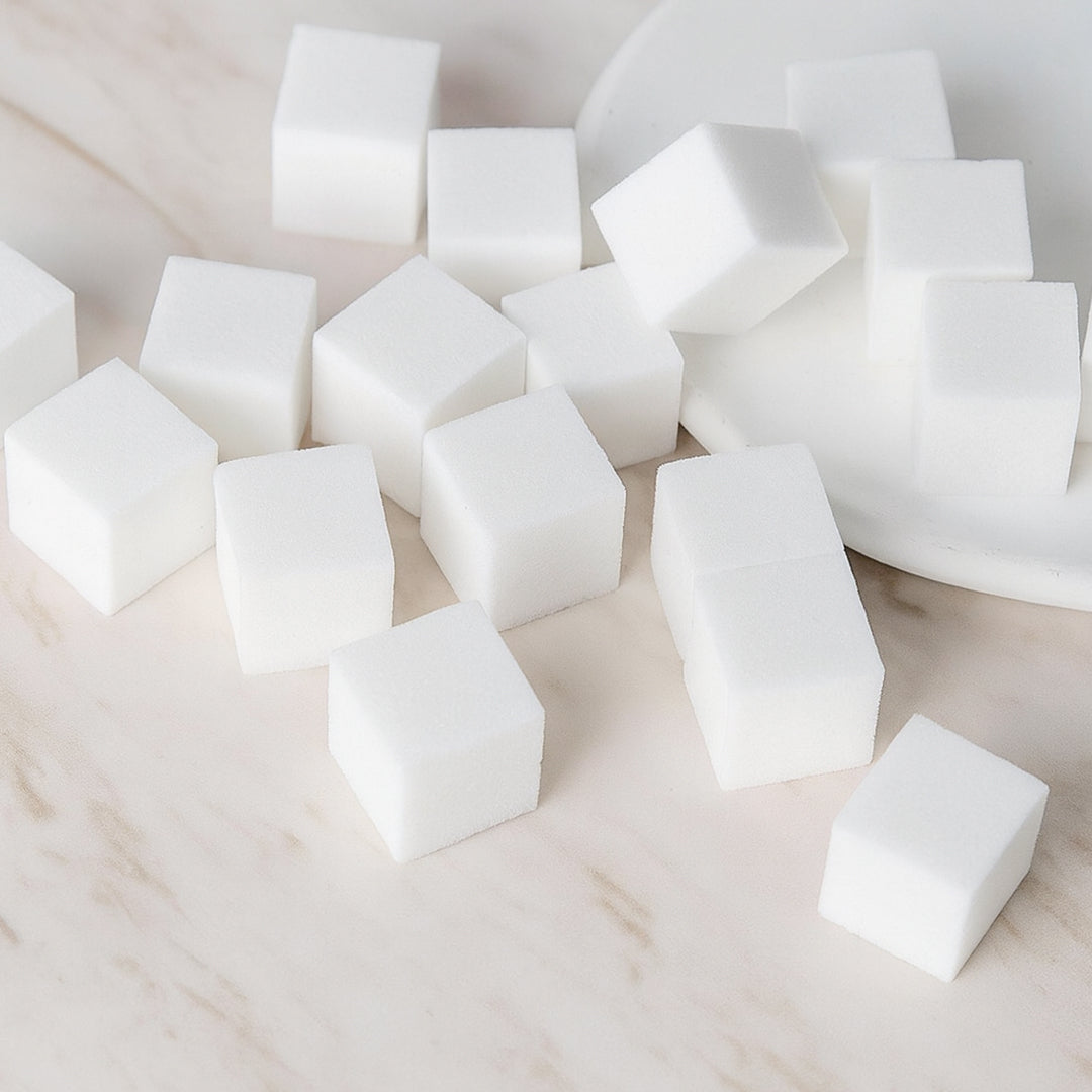 White nail sponge cubes displayed on a marble surface.