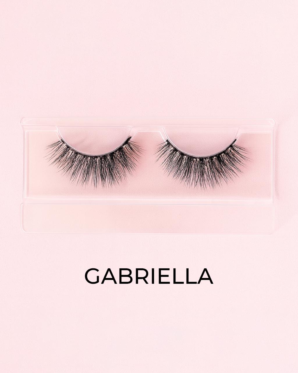 Pair of false eyelashes in a clear packaging with 'GABRIELLA' branding on a pink background.